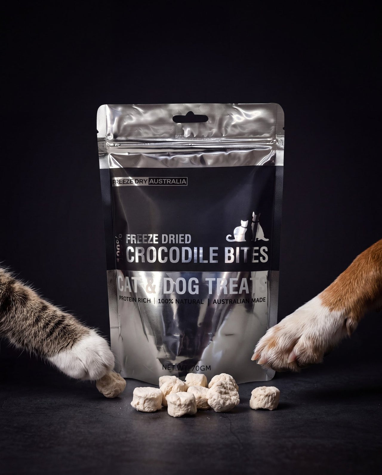 A cat paw and a dog paw reaching for a bag of Crocodile Bites